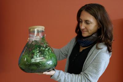Frau mit Pflanzen in großer Flasche