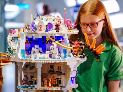 Mädchen betrachtet Haus aus Lego